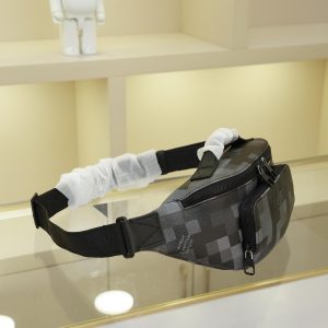 Alternative view of The Bumbag, crafted from Damoflage black canvas, is bold and modern—perfect for those seeking an effortlessly cool vibe. The iconic Damier pattern is cleverly pixelated, creating a unique camouflage effect against the black backdrop. An adjustable shoulder strap allows the Bumbag to be worn around the waist, over the shoulder, or crossbody. Dimensions: 30×15×8cm